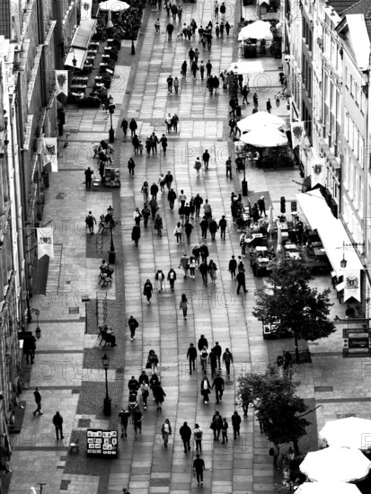 Black and white aerial view of a busy pedestrian zone with numerous passers-by and cafés, Gdansk, Poland