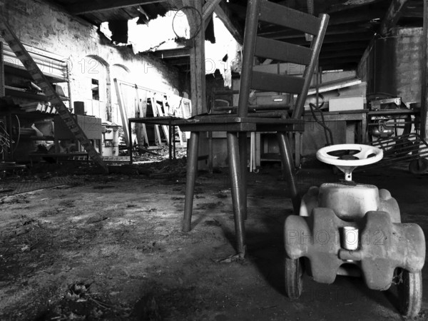 Abandoned industrial space with an old chair and a toy car on the floor, black and white, Upper Franconia