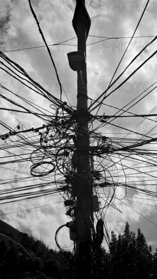 Complex network of cables on a power pole against a cloudy sky in black and white, Prizren, Kosovo