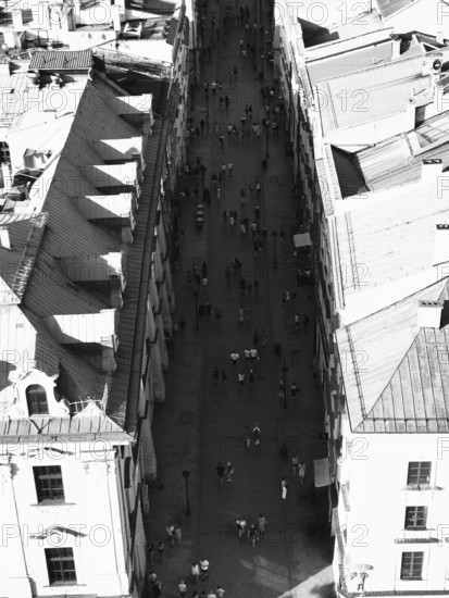 Aerial view of busy street between tall buildings in sunny atmosphere, black and white, Krakow, Poland