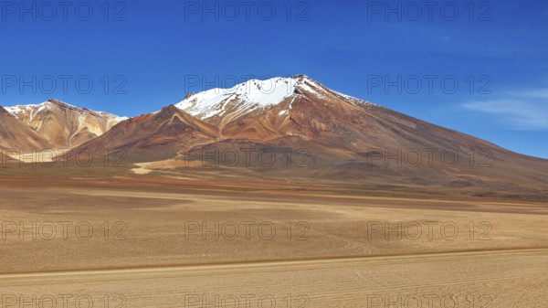 Majestic snow-capped mountain in front of a vast, sandy desert landscape, The landscape of the Altiplano in Bolivia