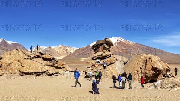 People climb rocks against a majestic mountain backdrop in the desert, The landscape of the Altiplano in Bolivia
