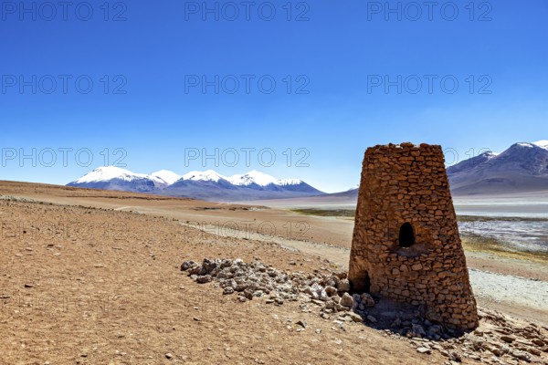 Ancient stone structure in a vast desert landscape with snowy mountains in the background, The landscape of the Altiplano in Bolivia