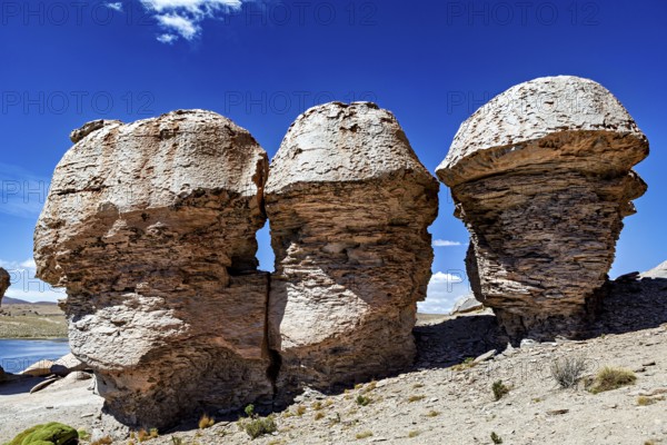 Three monumental rocks stand proudly in a dry desert landscape under clear blue skies, The Landscape of the Altiplano in Bolivia
