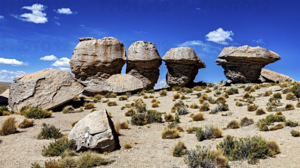Remarkable rock formations rise in a dry desert landscape under clear skies, The landscape of the Altiplano in Bolivia