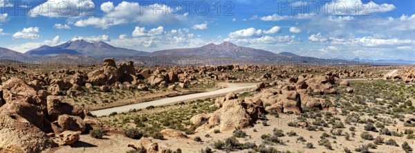 Wide panoramic landscape with large rocks, a dusty desert and mountains under a cloudy sky, The landscape of the Altiplano in Bolivia