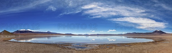Wide and open landscape with a lake under dramatic skies and distant mountains, The Laguna Colorada in the Altiplano in Bolivia