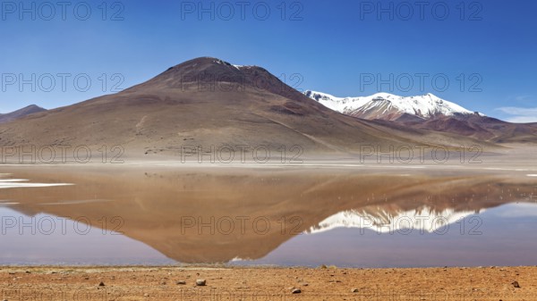 Lonely mountain landscape reflected in the still, clear water of a lake, Laguna Colorada in the Altiplano in Bolivia
