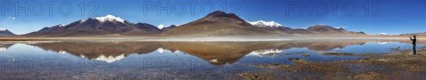 Wide panorama of mountains with reflecting lake and clear sky above the scene, Laguna Colorada in Altiplano in Bolivia