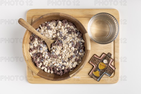 Wooden bowl with cereal and a cross on a wooden board with water, fasting