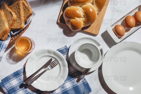 Breakfast items such as toast, stollen, eggs and honey on a white table