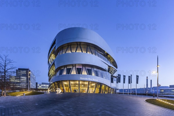 The Mercedes-Benz Museum in Stuttgart presents a journey through the automotive history of the global corporation. Spectacular architecture of the Automobile Museum in the evening. On the left, the headquarters of Mercedes-Benz Group AG. Untertürkheim, Stuttgart, Baden-Württemberg, Germany