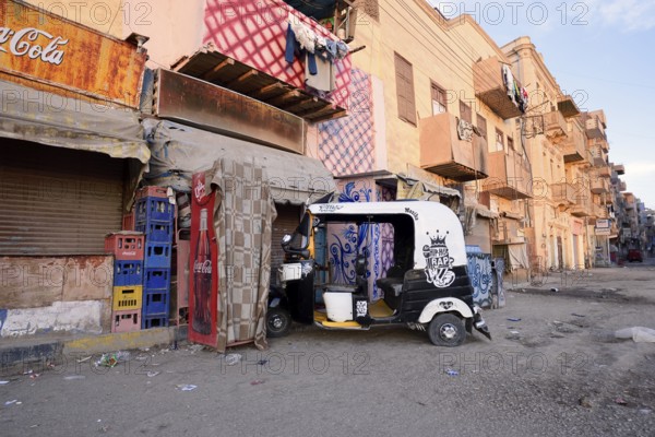 Street and a parked tuk-tuk in front of a shop, Esna, Egypt