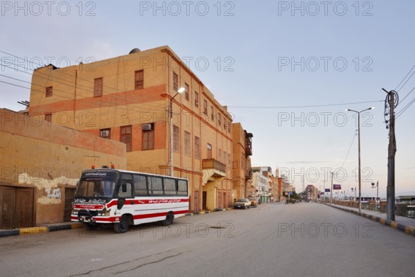 Bus parked on a street and houses, Esna, Egypt