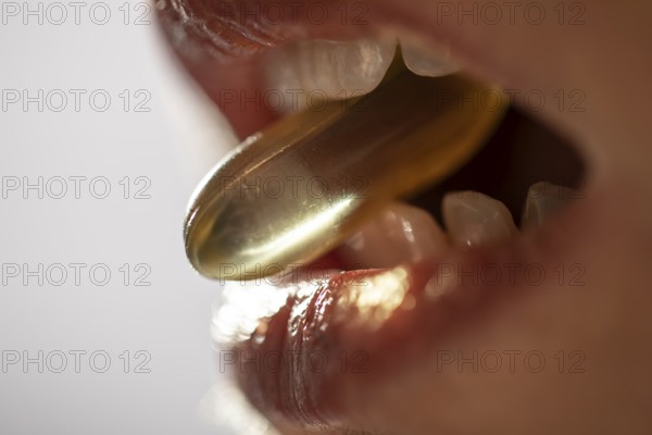 Close view of a woman mouth taking an omega 3 capsule