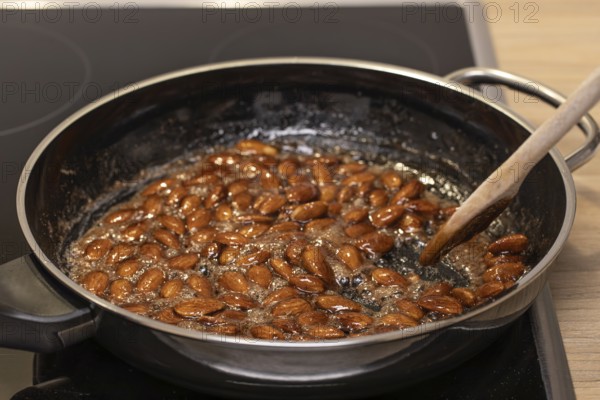 Almonds caramelized in a pan while stirred with a spoon. Germany