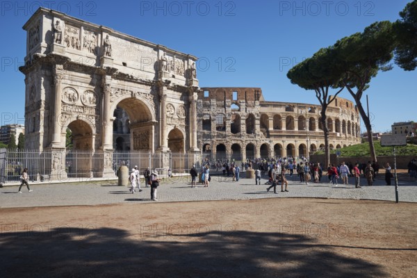 Arch of Constantine and Colosseum surrounded by tourists under blue sky, Rome, Lazio, Italy