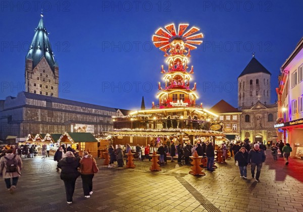 Christmas market with mulled wine pyramid on the market with St. Ulrich Cathedral and Gaukirche in the evening, Paderborn, North Rhine-Westphalia, Germany