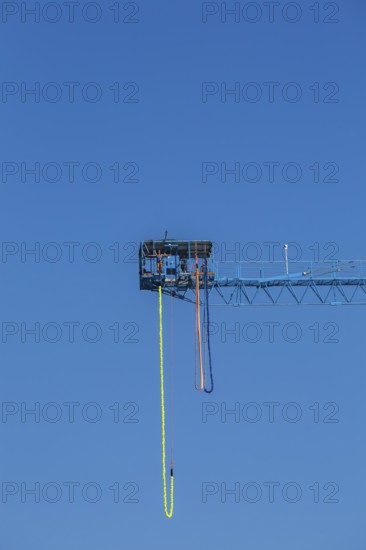 Montreal Bungee Tower installation with dangling long yellow elastic bungee jumping cord and woman ready to jump, Old Port of Montreal, Quebec, Canada