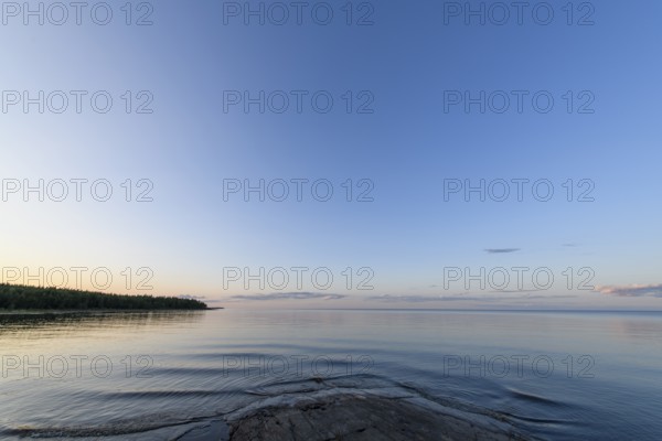 Far-reaching view of the quiet lake Vänern with gently sloping granite rocks archipelago under calm sky in the evening, Värmlands län, Sweden