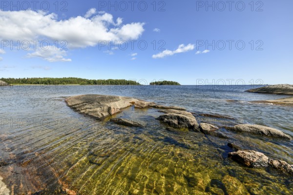 Clear sky over rocky archipelago coastline with granite archipelago with green forest and blue water at Lake Vänern, Värmlandsnäs peninsula, Värmlands län, Sweden