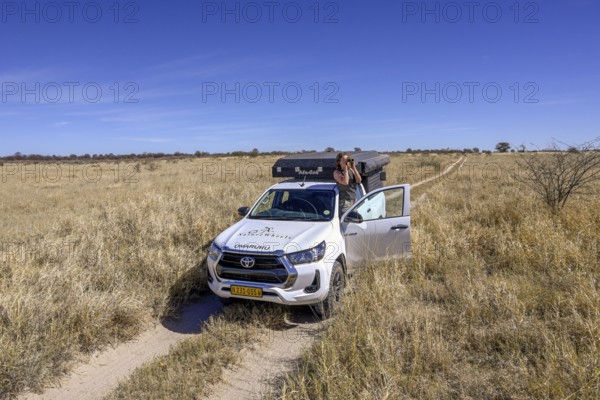 Tourist observes animals through binoculars near the Baines Baobabs, Nxai-Pan National Park, near Gweta, Central District, Botswana