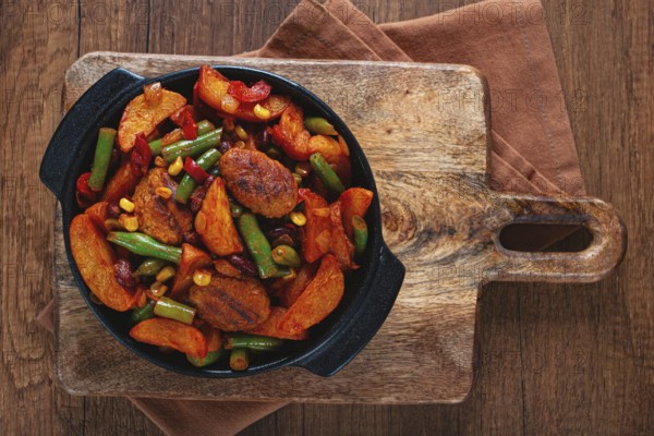 Steakhouse pfanne, fried potato slices, with meatballs, and vegetable mixture, on a black plate