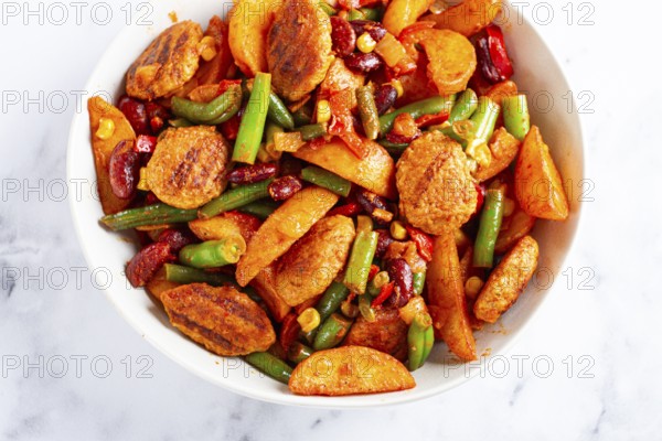 Steakhouse pfanne, fried potato slices, with meatballs, and vegetable mixture, on a white plate
