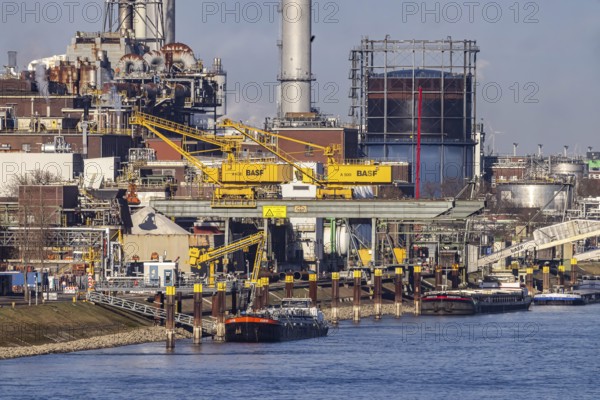 BASF factory site with chemical plants and chimneys. Baden aniline and soda factories. chemical plant. Port cranes unloading a cargo ship. Ludwigshafen am Rhein, Rhineland-Palatinate, Germany