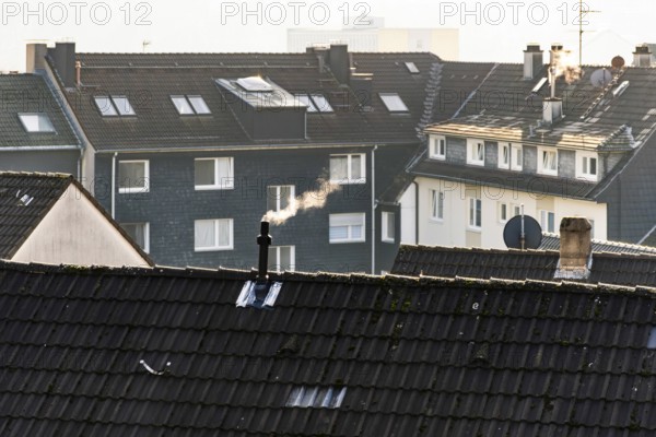 Smoke plume from a chimney over densely built residential area in the evening light, wintry city scene, Wuppertal, Germany