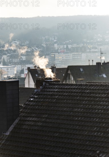 Smoke plume from a chimney over densely built residential area in the evening light, wintry city scene, Wuppertal, Germany