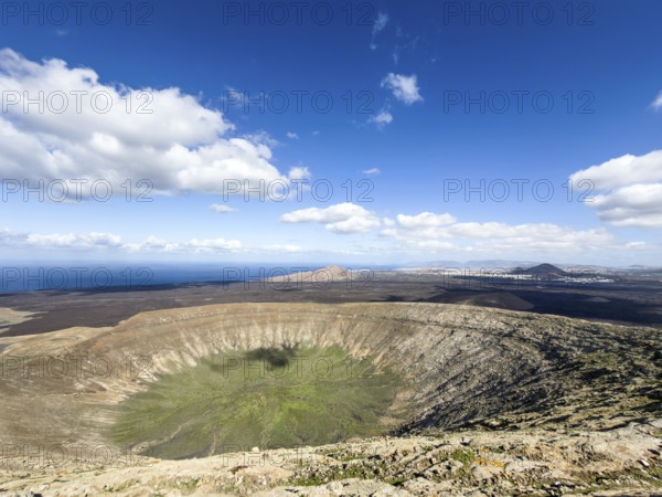 View of the Caldera Blanca volcano cauldron against blue sky with white clouds, Mancha Blanca, Lanzarote, Canary Islands, Spain