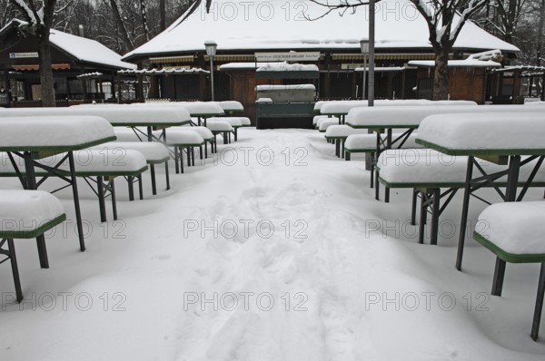 Winter in the English Garden, snow-covered beer garden tables and benches, Munich, Bavaria, Germany