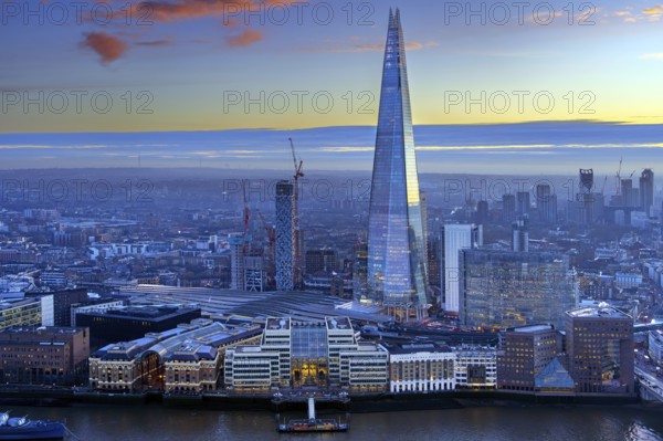 The Shard, pyramid-shaped skyscraper and London Bridge Station along the River Thames in Southwark at sunset at the capital city London, England, UK