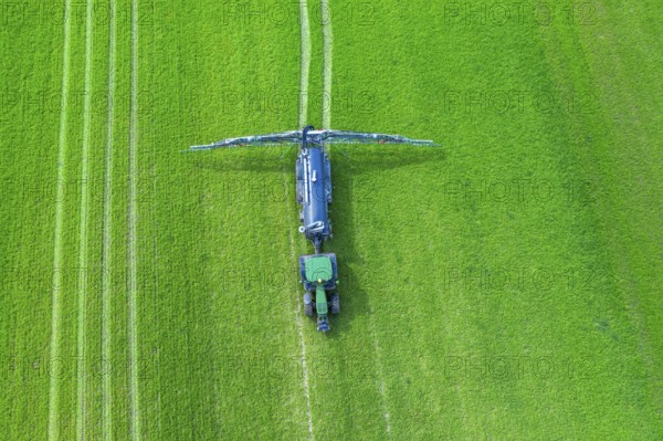 Aerial view over tractor towed liquid manure spreader, slurry spreader enabling the fertilization of arable land by distributing slurry in spring
