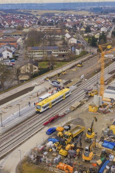 Construction site with crane and yellow train at a municipal train station, surrounded by buildings, acceptance of the Hermann Hesse Railway, Calw, Black Forest, Germany