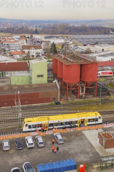 Aerial view of an industrial area with a yellow train and large red buildings, taking the Hermann Hesse Railway, Weil der Stadt, Black Forest, Germany