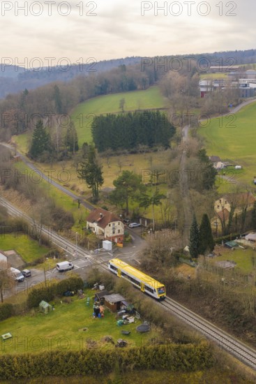 Rural scene with yellow train in green countryside and scattered houses, acceptance of the Hermann Hesse Railway, Calw, Black Forest, Germany