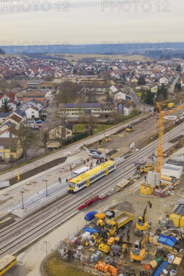 Aerial view of a city with a construction site and a yellow train on the tracks, construction cranes visible, the Hermann Hesse Railway, Althengstett, Black Forest, Germany