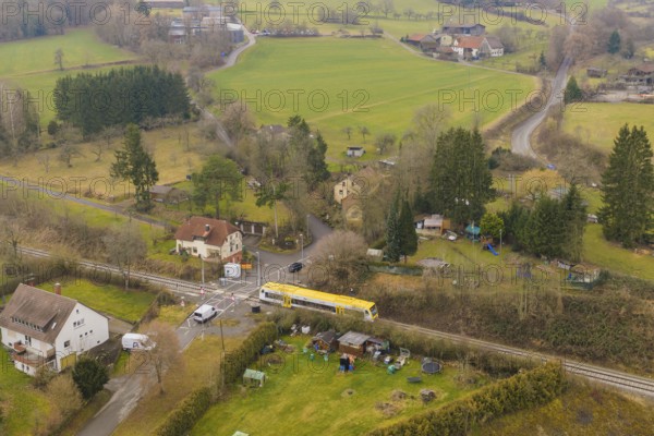 Rural landscape with individual houses, fields and a yellow train on the tracks, acceptance of the Hermann Hesse Railway, Calw, Black Forest, Germany