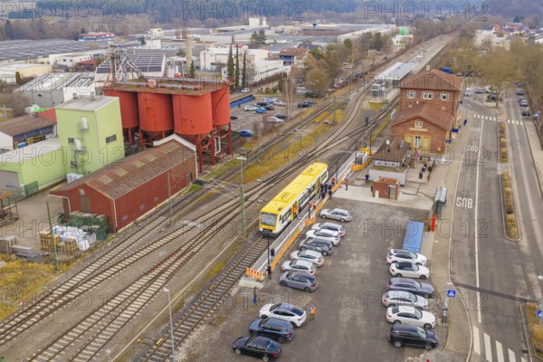 Railway station with yellow train in a rural area, surrounded by cars and buildings, acceptance of the Hermann Hesse Railway, Weil der Stadt, Black Forest, Germany