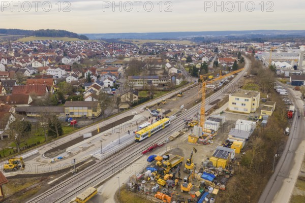 Aerial view of urban construction site with yellow train on tracks and residential buildings, acceptance of the Hermann Hesse Railway, Althengstett, Black Forest, Germany