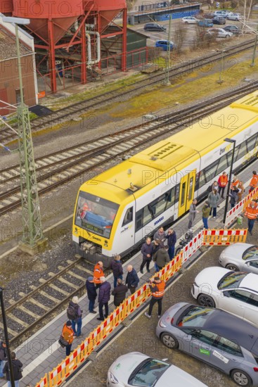 A yellow train at a train station with people and parked cars on the side, acceptance of the Hermann Hesse Railway, Calw, Black Forest, Germany