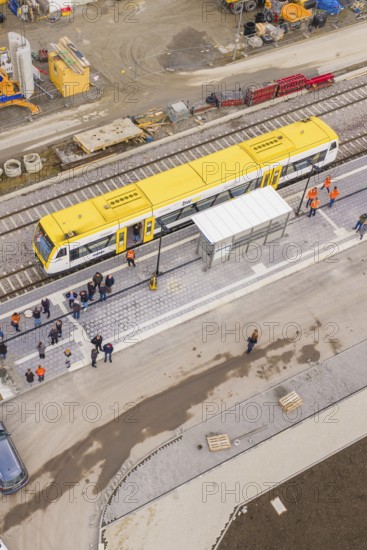 A bird's eye view of a yellow train at a train station with people, taking the Hermann Hesse Railway, Calw, Black Forest, Germany
