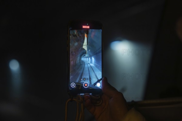 A smartphone shows a picture of a tunnel with rails, the Hermann Hesse Railway, Calw, Black Forest, Germany