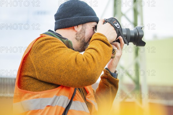 A photographer wears a safety vest and takes pictures at work, taking the Hermann Hesse Railway, Calw, Black Forest, Germany