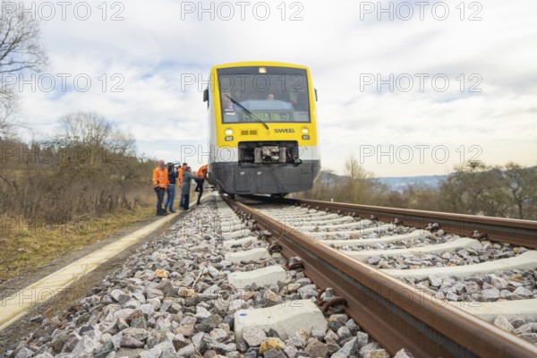 A train travels through a rural landscape with waiting passengers, taking the Hermann Hesse Railway, Calw, Black Forest, Germany