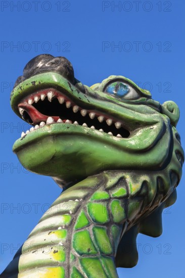 Green dragon with big teeth and long red tongue against blue sky background, Fun Show traveling amusement ride park, Old Port of Montreal, Quebec, Canada