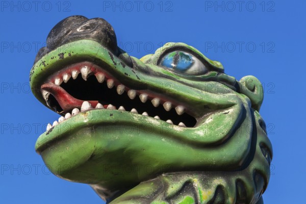 Green dragon with big teeth and long red tongue against blue sky background, Fun Show traveling amusement ride park, Old Port of Montreal, Quebec, Canada