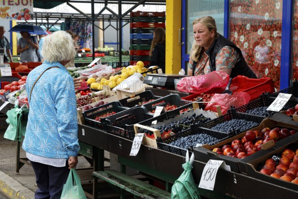 Saleswoman presents fruit and vegetables at the Central Market in Riga, Riga, Central Market, Latvia